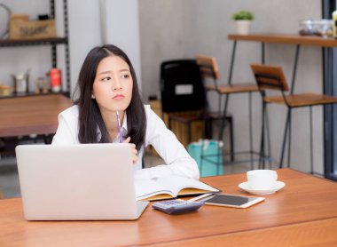 Dizüstü bilgisayar ile online çalışan Asyalı genç kadın ve proje f düşünüyorum
