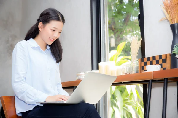 Hermosa mujer joven asiática trabajando en línea en el ordenador portátil sentado en —  Fotos de Stock