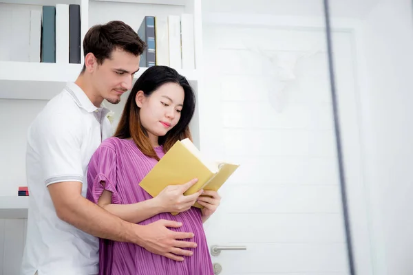 Husband with pregnant woman reading yellow book together, Portra — Stock Photo, Image