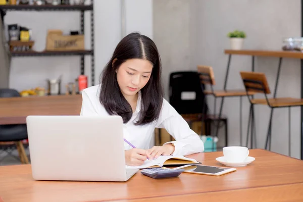 ビジネスアジアの女性は、ラップトップ、gとテーブルの上にノートブックに書き込み — ストック写真
