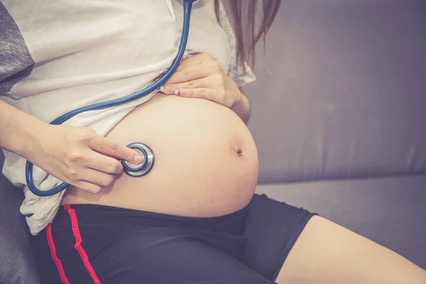 Primer plano de hermosa embarazada asiática mujer a embarazada escuchar —  Fotos de Stock