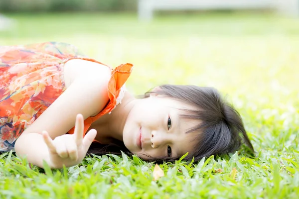 Piękny portret trochę Dziewczyna Asian z a uśmiechnięty leżący na zielony — Zdjęcie stockowe