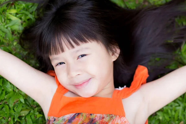 Schönes Porträt kleines asiatisches Mädchen von einem lächelnden Liegen auf Grün — Stockfoto