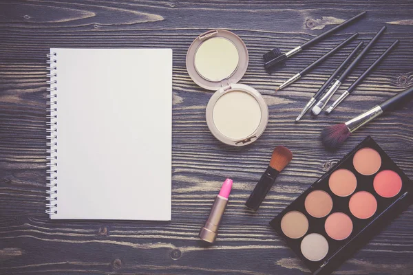 Widok z góry zbiór kosmetycznych makijażu i notebooka na drewnianych — Zdjęcie stockowe