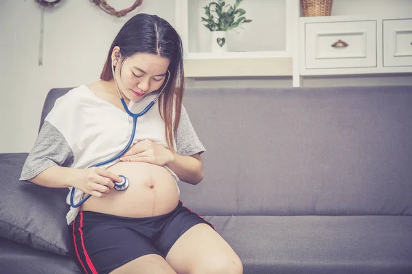 Primer plano de hermosa embarazada asiática mujer a embarazada escuchar —  Fotos de Stock