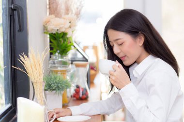 Güzel genç asyalı kadın kahve içme ve mo gülümseme