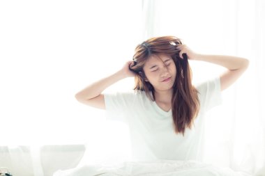 Güzel genç asyalı kadın streç ve uyandıktan sonra yatakta dinlenmek 