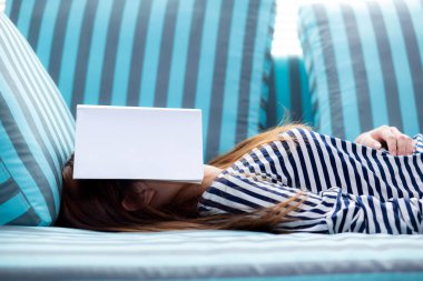 Kitap kaplama ile kanepede uyuyan güzel genç asyalı kadın 