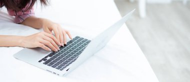 Banner web sitesi asya genç kadın yatakta dizüstü bilgisayar kullanarak yalan