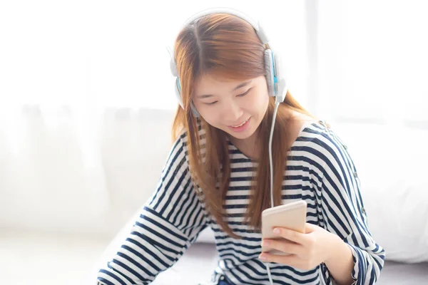 Güzel asyalı genç kadın kulaklık ile müzik dinlemek keyfini çıkarın bir — Stok fotoğraf