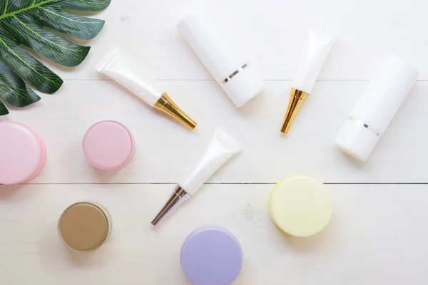 kozmetik ve cilt bakım ürünü ve beyaz ahşap ta yeşil yaprakları