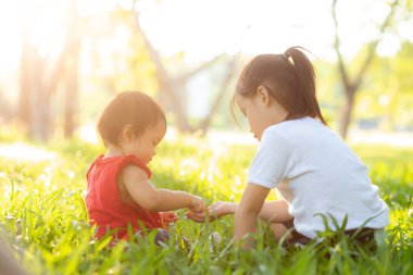 Güzel Asyalı çocuk yazın parkta oturuyor. 