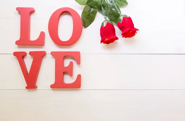 Word LOVE wooden text and red rose flower vintage on wood table