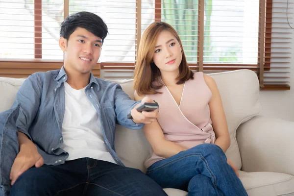 Bonito jovem asiático casal segurando remoto e assistindo tv ou v — Fotografia de Stock