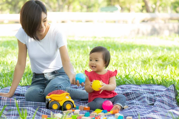 Güzel Asyalı genç anne ve kız, le için oyuncak blokları oynuyorlar.
