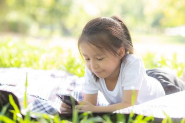 Gada akıllı cep telefonu kullanarak gülümseyen güzel Asyalı çocuk.