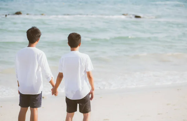 Pasangan gay Asia berpegangan tangan di pantai dengan santai — Stok Foto