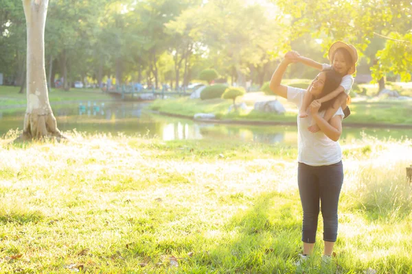 Schöne junge asiatische Mutter trägt kleine Tochter mit Lächeln — Stockfoto