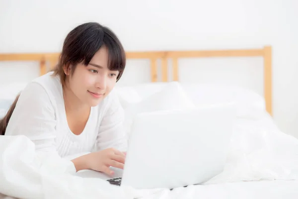 Hermoso retrato asiático joven sonrisa acostada en la cama usando la — Foto de Stock