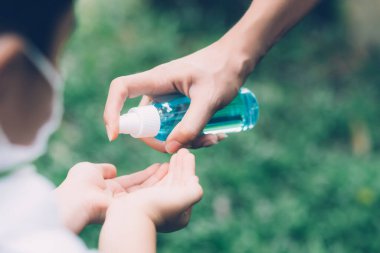 Anne, yüz maskesi ve dezenfektan ile dikkat et. Grip veya açık hava gribi için dezenfektan. Anne ve çocuk sağlık maskesi takıyor..