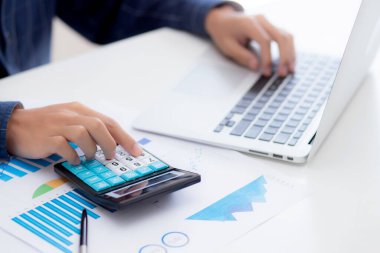 Muhasebecilik için hesap makinesi kullanan genç Asyalı iş adamının eli, finans ve rapor grafiği, istatistik, yatırım ve gelir kârı, grafikle analiz eden iş adamı.