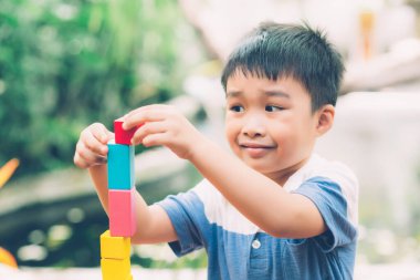 Asyalı genç çocuk, yaratıcı ve gelişim için masada tahta blok oyuncağı oynuyor. Mutlu çocuk, etkinlik bulmacası için beceri ve evde oyun için yaratıcılık öğreniyor. Eğitim kavramı..
