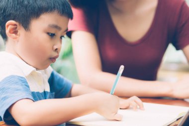 Evlat çalışmak için dijital tablet bilgisayar kullanıyor ve interneti annesiyle birlikte öğreniyor, evden eğitim, aile eğlencesi, anne çocuğa ve ev ödevlerini teknoloji, yaşam tarzı konsepti ile öğretiyor..