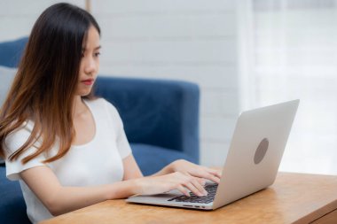 Evdeki dizüstü bilgisayarda klavye yazan genç Asyalı güzel bir kadın. İnternette çalışan bir iş kadını. Masada not defteri, iletişim ve yaşam tarzı konsepti kullanan serbest bir kız..