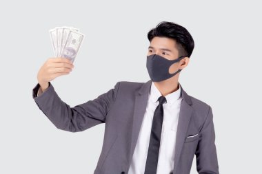 Yüz maskeli genç Asyalı işadamı para dolarını beyaz arka planda, salgın hastalıkta ve ekonomik krizde, tıbbi maske takan ve hastalık sırasında yatırım yapan işadamında izole etti..