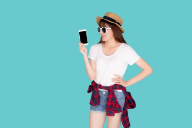 Güzel, genç Asyalı bir kadın yaz tatili seyahatlerinde sunum yapmak için akıllı cep telefonu kullanıyor mavi arka planda izole edilmiş Asyalı bir kız akıllı telefon tutuyor, tatil kavramı..