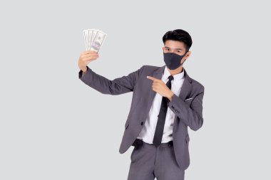 Yüz maskeli genç Asyalı işadamı para dolarını beyaz arka planda, salgın hastalıkta ve ekonomik krizde, tıbbi maske takan ve hastalık sırasında yatırım yapan işadamında izole etti..
