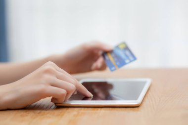 Genç Asyalı kadının kredi kartı alışverişini elinde tutan eli tablet bilgisayarlı boş ekran alımı ve ödemesi, bankamatik kartı veya alım-satım, e-ticaret konsepti kullanan kız.