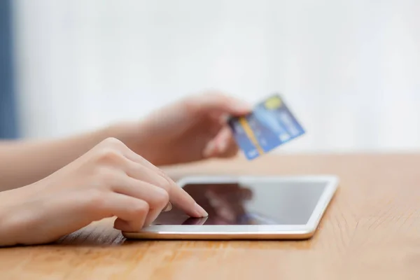 Closeup hand of young asian woman holding credit card shopping online with tablet computer blank display screen buying and payment, girl using debit card purchase or transaction, e-commerce concept.