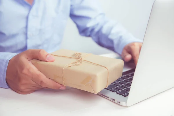 男人的手拿着牛皮纸礼品盒 桌上放着手提电脑 在网上购物 为圣诞节或结婚周年纪念日送礼 在社交场合庆祝 — 图库照片