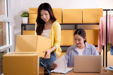 İki genç Asyalı iş kadını dizüstü bilgisayar ve belge, sevkiyat ve kargo, perakende satış ve mağaza, başlangıç veya küçük işletme, nakliye ve envanter siparişlerini kontrol ediyor.