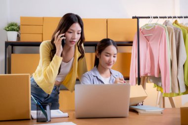 İç işlerinde iki Asyalı kadın e-ticaret girişimi, iki genç girişimci yönetim emri, çevrimiçi satıcı takım çalışması, hazırlık dağıtımı için ürün paketleme, perakende ve nakliye, iş konsepti.