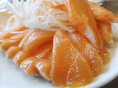 Somon parçaları ve yengeç sopa kesilmiş beyaz plaka üzerinde