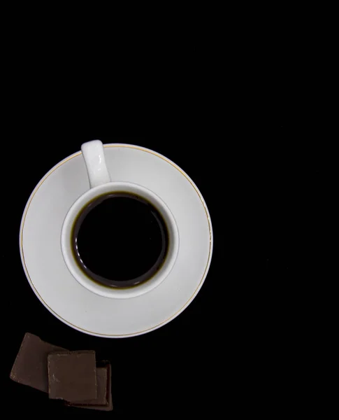 Sluiten zwarte hete koffiekop en rook met latte art foam op zwarte houten tafel in cafe.dark scene.banner ruimte mock up voor het toevoegen van tekst — Stockfoto