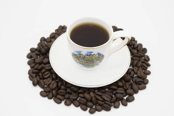 Кофейная чашка и кофейные зёрна на белом фоне — стоковое фото