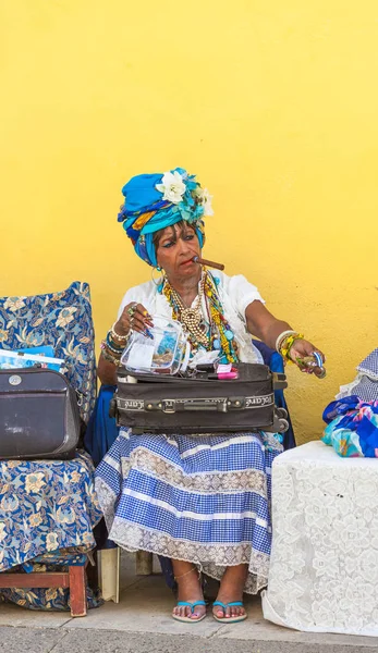 Havana, Küba-Ekim 8, 2016. Küba yerli, ilginç, eski Bayan geleneksel giysilerle sokakta onu her zamanki yaşam tarzı 8 Ekim 2016 Havana şehrin eski kesiminde oturan puro ile giyinmiş.