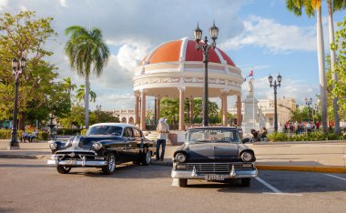 Cienfuegos, Cuba-Ekim 13, 2016. Eski arabalar ve rotunda Merkez Meydanı, park ve Bahçe denilen Parque Jose Marti üzerinde 13 Ekim 2016 Cienfuegos Güney sahil kasabasında sömürge döneminden kalma binalar ile.