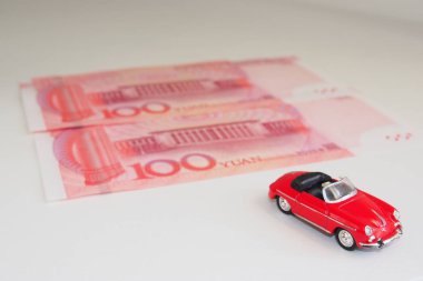 Model araba ve Rmb banknotları. Banknotların arka planında spor model, kırmızı, üstü açılabilir, Rmb. Metin için alanı kopyala.