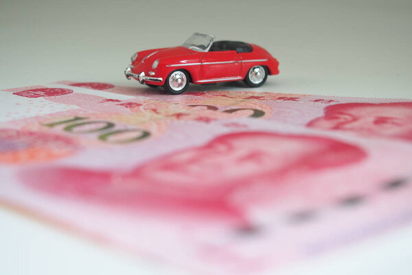 Model car and RMB banknotes. Model sports red vintage convertible on the background of banknotes - RMB.  Copy space for text.