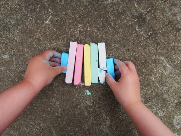 野外での教育ゲーム 子供の手にチョークパステルカラーの作品 — ストック写真