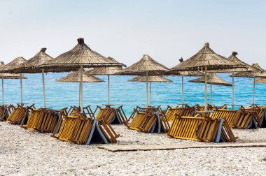 Denizden boş şezlonglar. Bir gölgelik altında. Borsh Arnavutluk