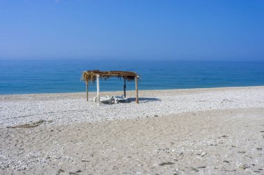 Denizden boş şezlonglar. Bir gölgelik altında. Borsh Arnavutluk
