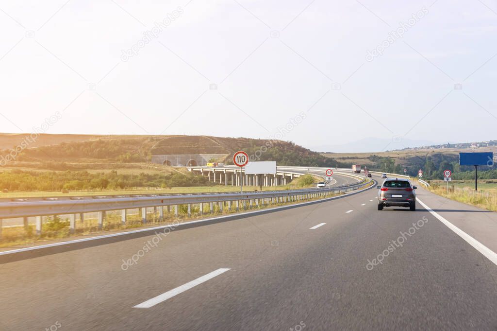  crossover car driving fast on asphalt road. the road in front of the tunnel. speed limit signs