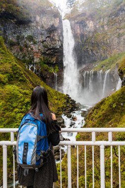Genç kadın turist ayakta bakmak ve manzarayı, Kegon Şelalesi'nde doğanın Güz Nikko Milli Parkı, Japonya.