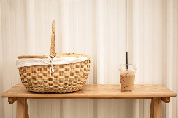 Frappucino misto freddo in tazza di plastica e cestino da picnic su legno Fotografia Stock