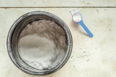 beyaz toz ve servis kaşığı ile siyah plastik kavanoz